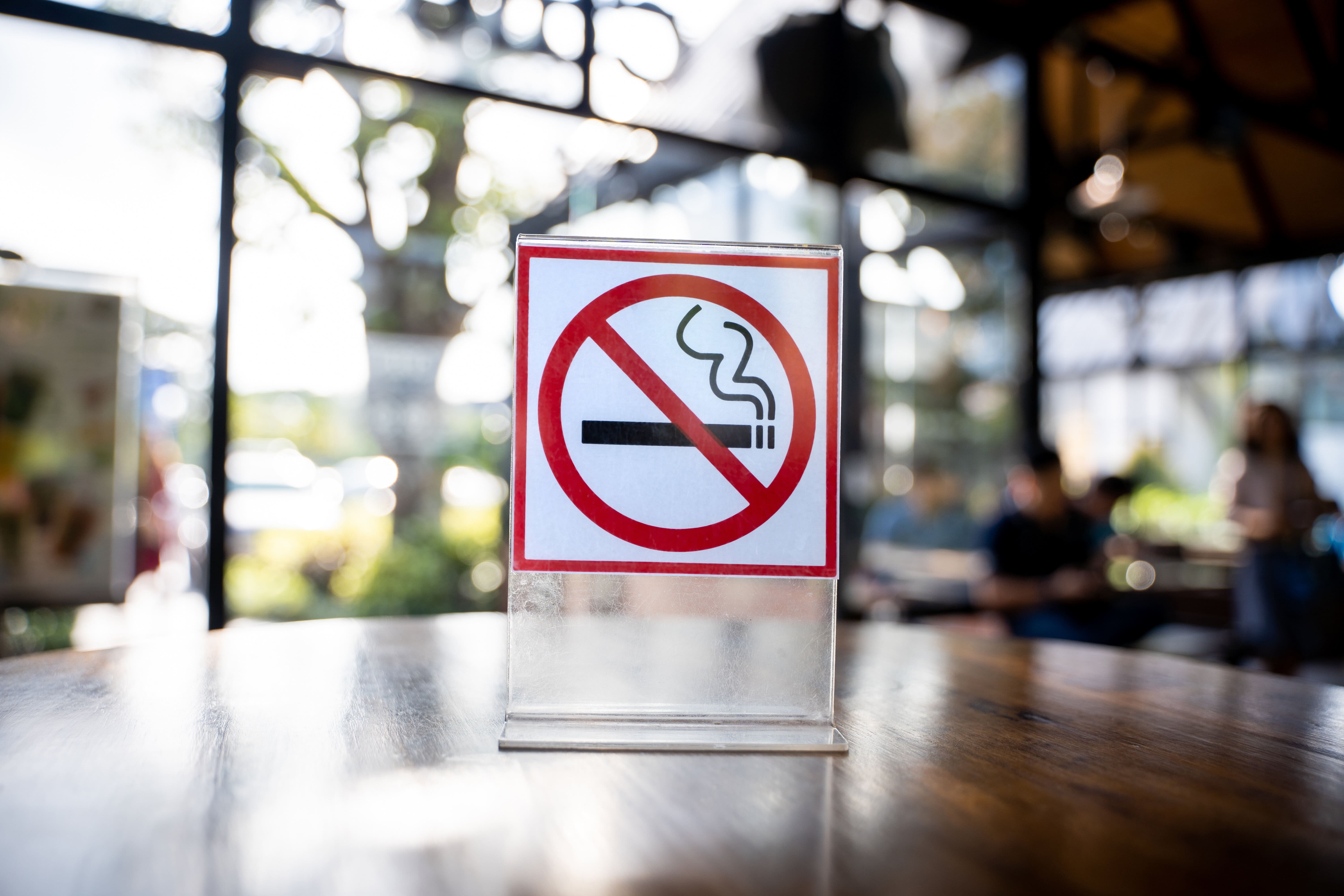 Sign on a table with a cigarette in a slashed red circle 