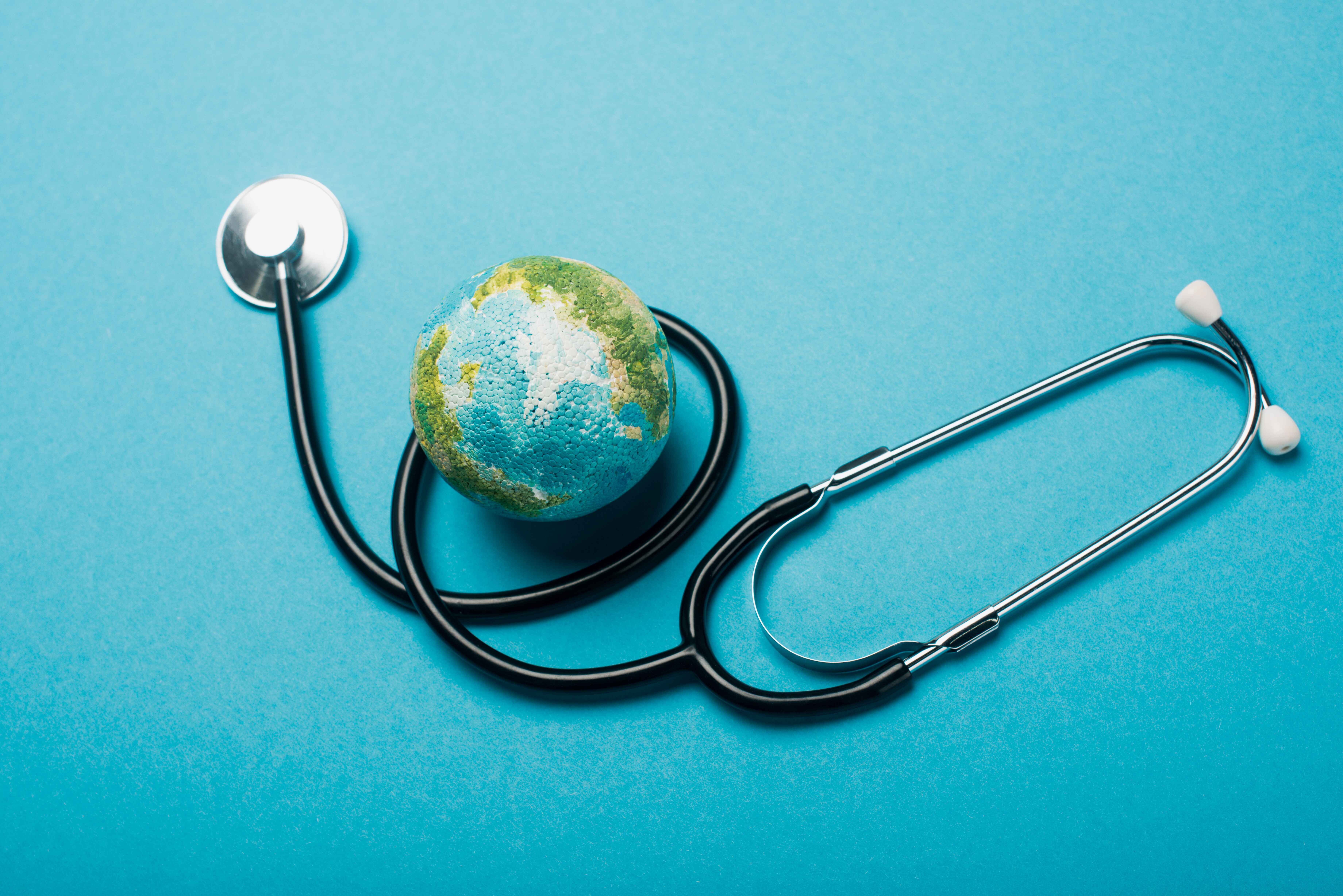 A small globe with a stethoscope wrapped around it on a blue background.