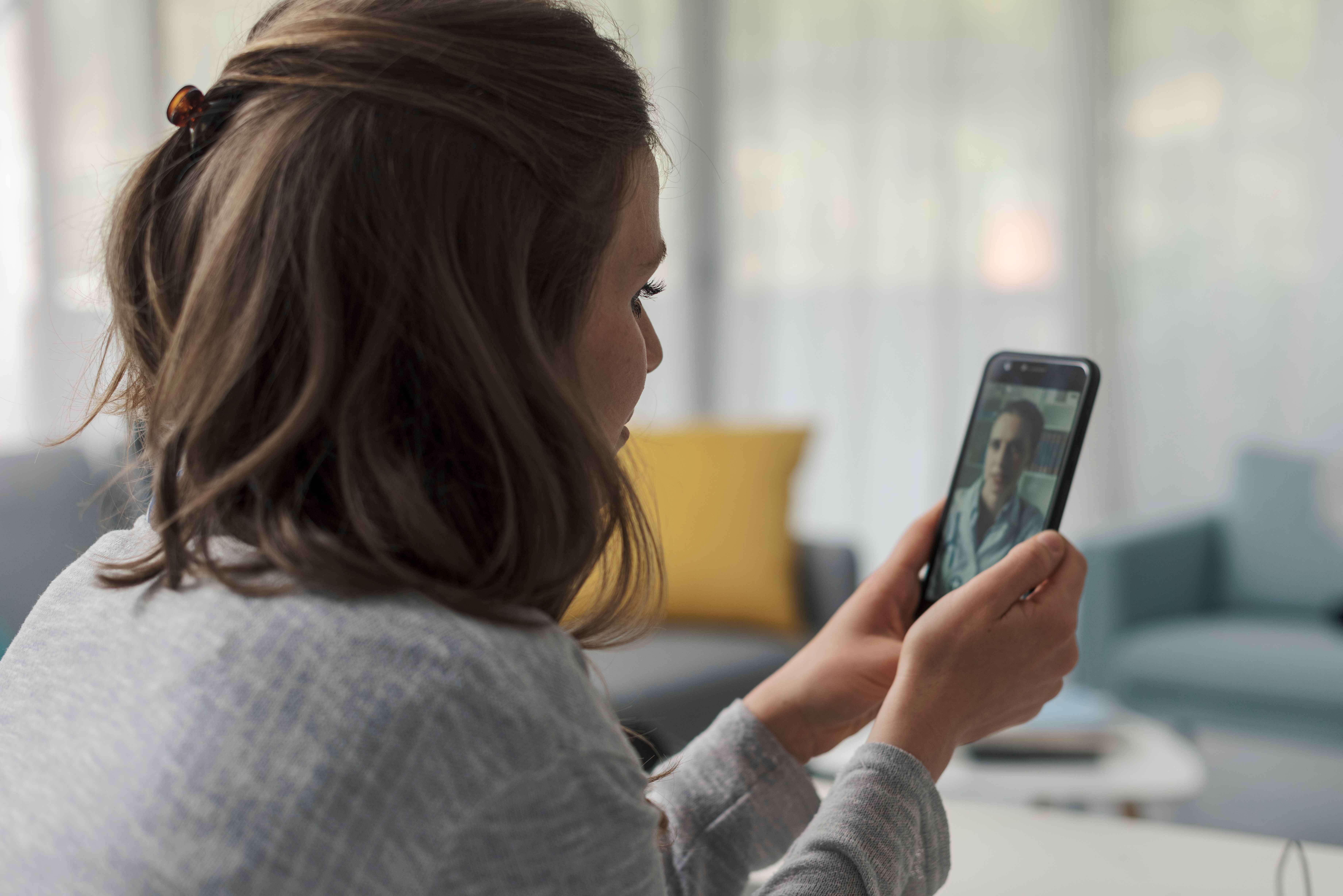 Woman video calling on her smartphone while sitting indoors.