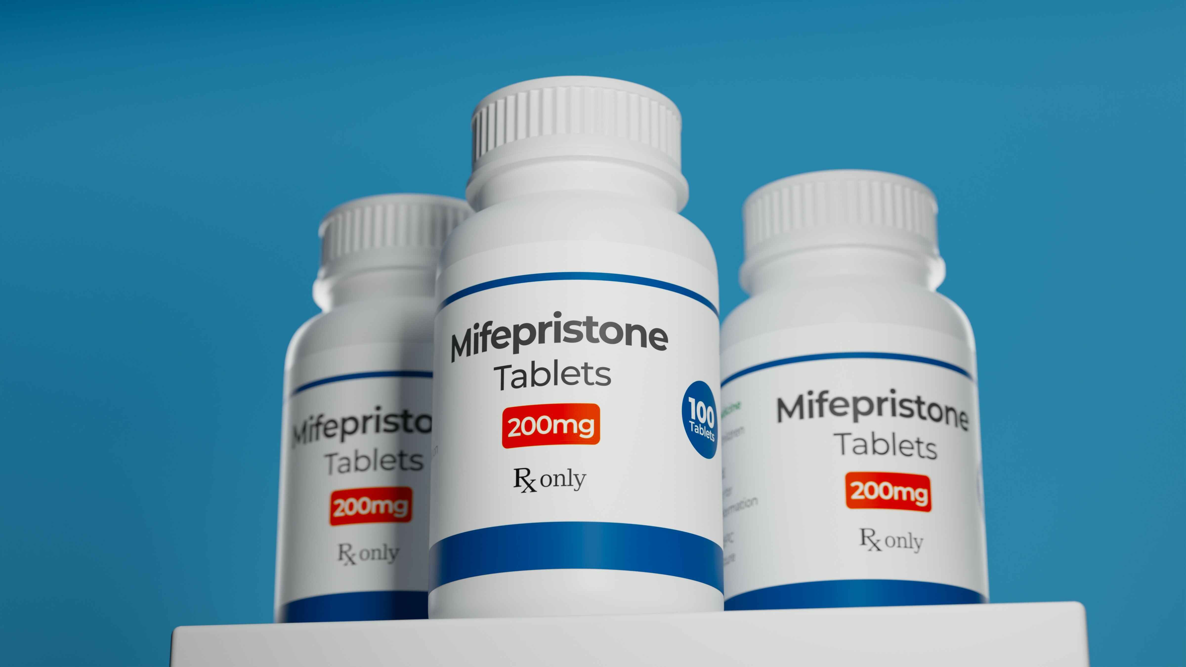 Three bottles of Mifepristone Tablets against a blue background.