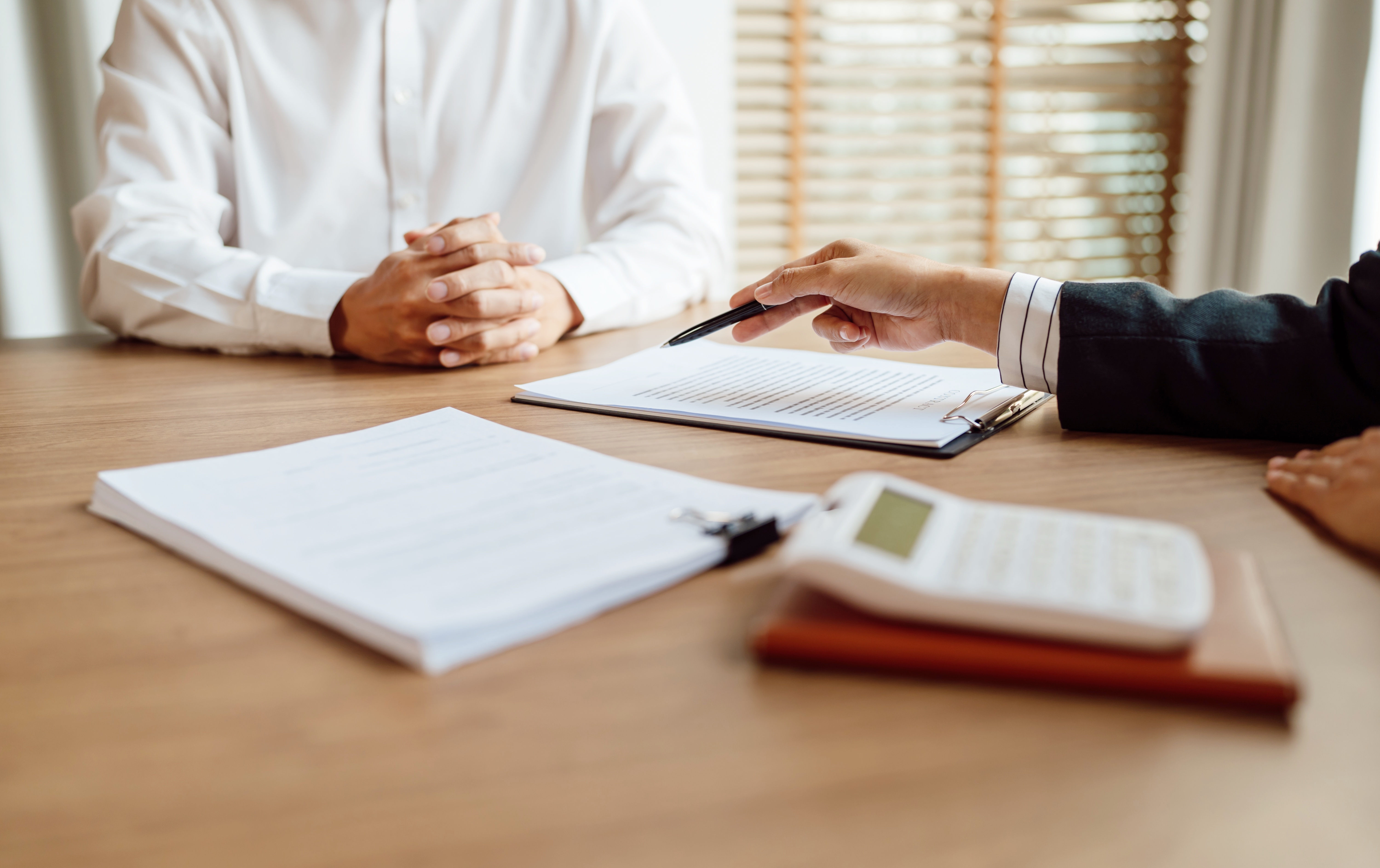 Two people at a table, one pointing at a document with a pen.