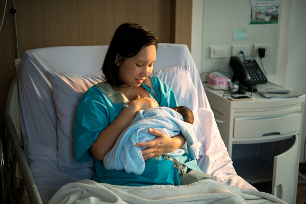 Mother breastfeeding newborn in a hospital bed