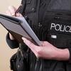Person in a police vest writing in a notebook.