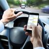 Person using a smartphone while driving, with messaging app open.