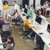 An open-plan office with people working at desks and conversing