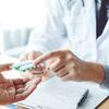 Healthcare professional handing a blister pack of pills to a patient.