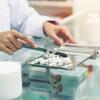 Pharmacist sorting white pills on a metal tray with a spatula.