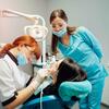 A dentist and assistant perform a dental procedure on a patient in a dental clinic.