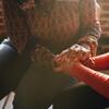 Two people with their faces obscured holding hands