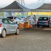 Drive-through COVID-19 testing site with cars under tents and personnel in protective gear.