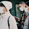 A group of people wearing face masks, standing outdoors.