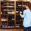 Woman browsing wine bottles on wooden shelves in a store.
