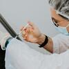A person in protective gear administers an injection to a person out of frame