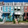 Row of colorful townhouses with similar architectural features.